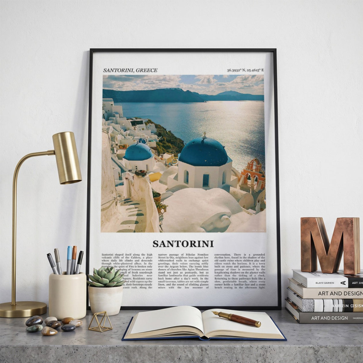 Ingelijste Santorini Fotoposter – Kleur op een bureau in zwarte fotolijst